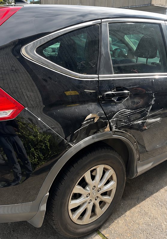Black SUV with a dented rear door before repair